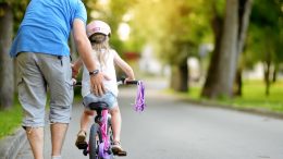 Maman qui tient une petite fille qui s'initie au vélo