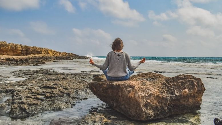 Femme qui médite sur une roche au bord de la mer