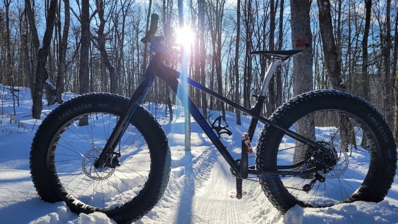 Vélo de montagne aux pneus surdimentionnés sur une piste enneigée.